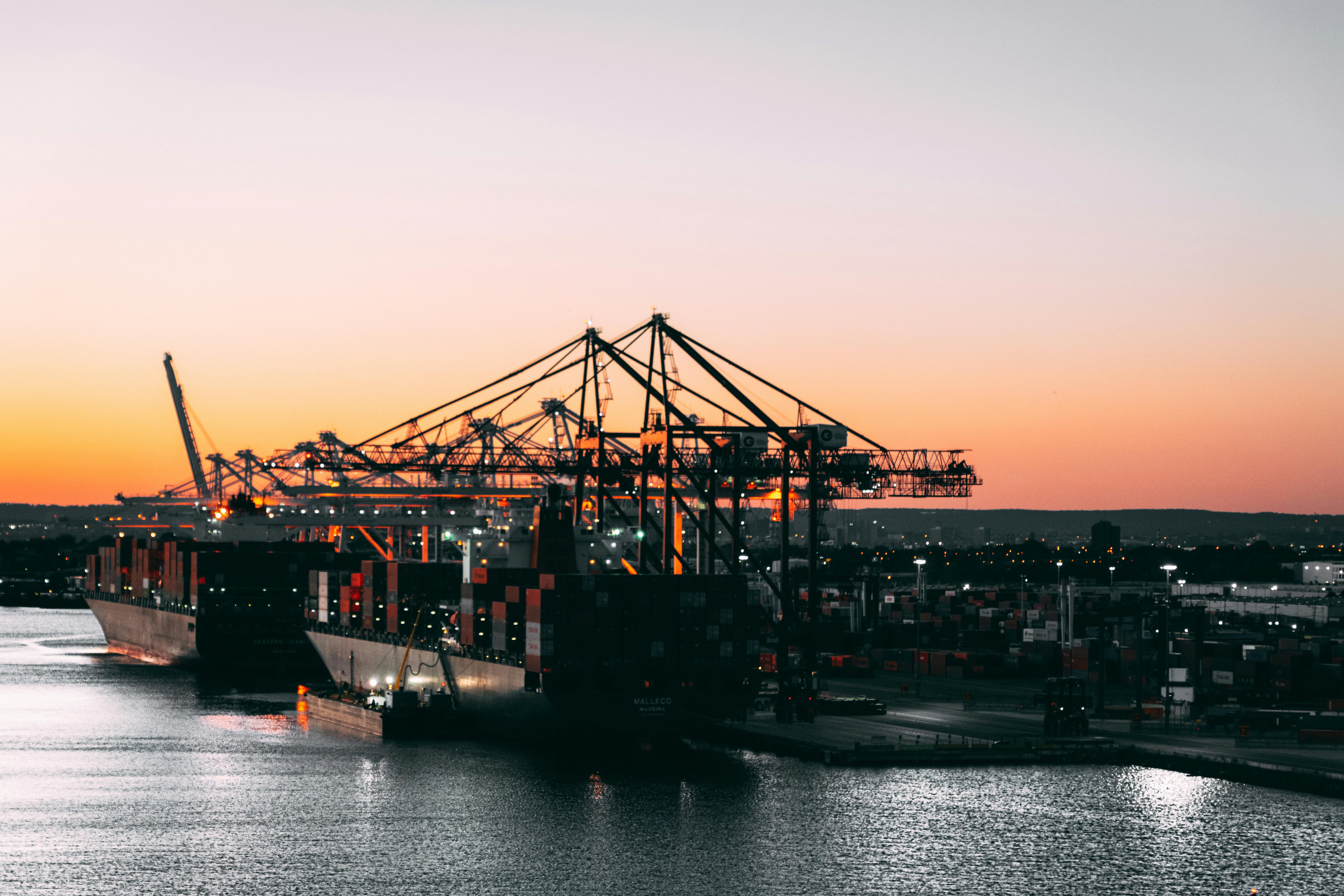 Shipping port at sunset with cargo cranes